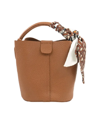A brown pebbled leather bucket bag with a top handle and a patterned scarf tied to the side, shown on a white background with a browser bar at the bottom.