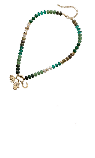 Two beaded charm necklaces displayed on a light beige background, shown in a split-screen layout. The top necklace features green, teal, and white faceted beads with gold-toned charms including a crescent moon, sun, and heart.