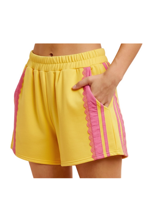 Yellow shorts with pink accents worn by a person on a white background