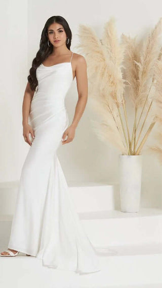 Woman in a white evening gown standing next to pampas grass against a white background