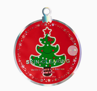 A round red holiday ornament-shaped facial mask package with a silver holographic border, featuring a green Christmas tree illustration and the text 'SKIN-CLEARNING' and 'Vanilla Extract & Milk Essence Facial Mask'.