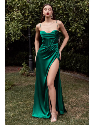 Woman in a green evening gown standing outdoors with greenery in the background