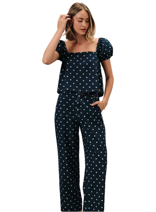 Woman wearing a navy polka dot outfit against a gray background