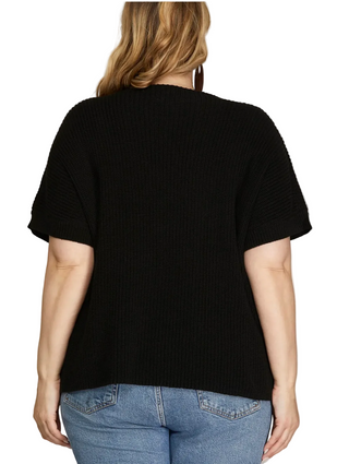 Person wearing a black sweater and blue jeans on a gray background