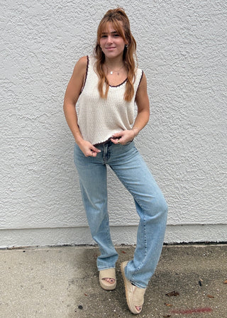 Girl wearing light wash jeans against a grey wall background.