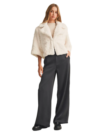 a woman wearing Faux Fur Jacket in cream with gray pants. 