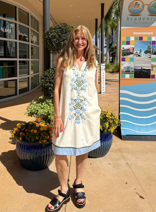 Woman in a white dress standing in front of a building with a 'Bradenton' sign.