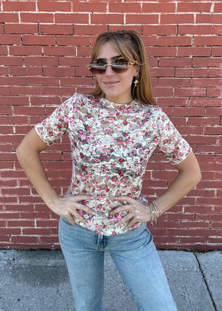 Person wearing a floral shirt and sunglasses on a red brick sidewalk