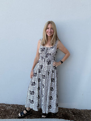 Woman wearing a black and white patterned dress against a light blue wall.