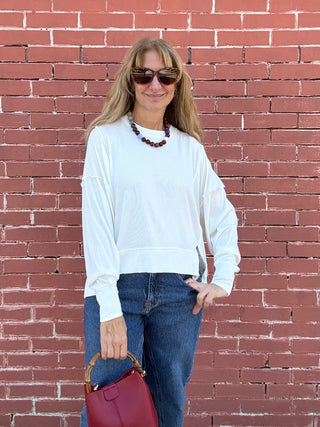 A woman wearing a white Free People All My Love Long Sleeve Top.