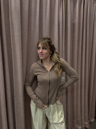 Woman lying on a large brown inflatable mattress against a neutral background