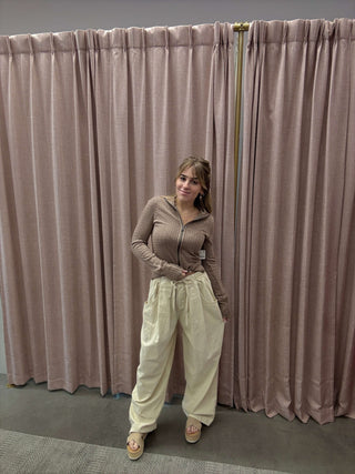 Person standing in front of a pleated curtain with a neutral color palette
