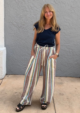woman wearing striped drawstring pull on pants standing against a blue wall