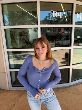 Woman in a purple cardigan standing in front of a store window
