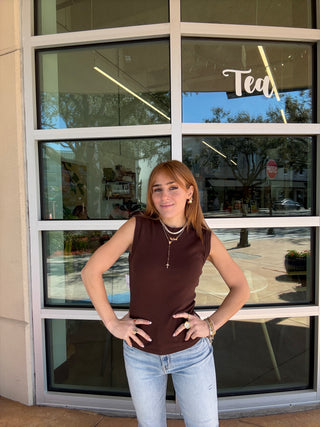 Person posing in front of a store window with 'Tea' sign