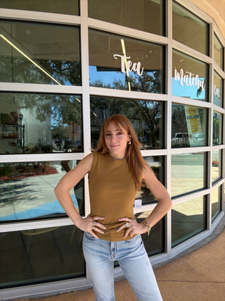 Woman posing in front of a glass building with 'Tilly's' sign.
