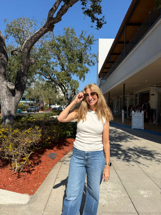 Woman standing on a sidewalk with trees and a building in the background