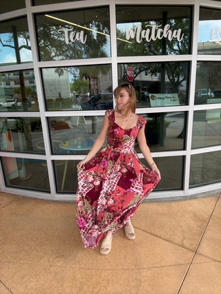 Woman in a red floral dress standing in front of a glass door with reflections.
