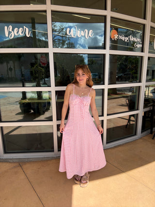 Woman in a pink dress standing in front of a glass door with reflections.