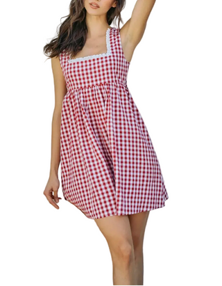 A woman wearing a red and white gingham check sleeveless mini dress with a square neckline and white lace trim, holding a beige straw hat against a plain light gray background.