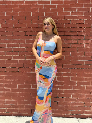 Woman in a colorful dress standing against a red brick wall