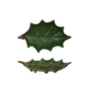 Two green holly leaf-shaped ceramic dishes with small red stem accents, shown on a plain white background.