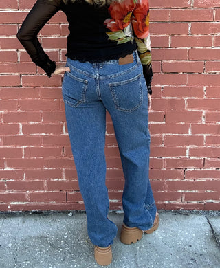 a woman wearing We The Free Risk Taker Mid-Rise Jeans - Be Bold medium wash denim jeans