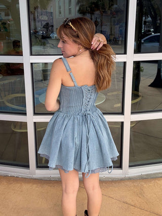Woman in a blue dress standing in front of a glass building