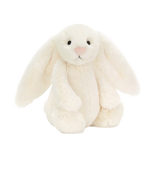 A cream-colored plush bunny toy with long floppy ears, black bead eyes, and a pink stitched nose, shown on a white background with product text below reading 'Bashful Cream Bunny' and a price of $33.00 USD.