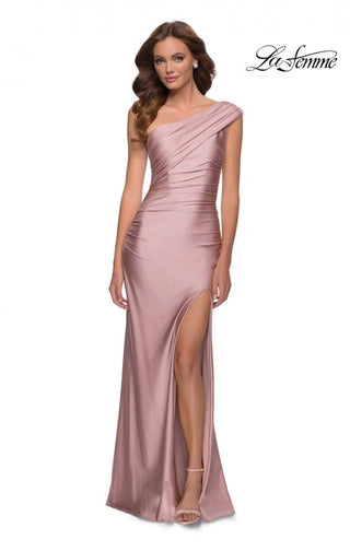 Model wearing a one-shoulder pink evening gown with a slit on a white background, branded 'La Femme'.