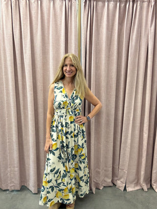 Woman wearing a Lemonade Scalloped Lace Maxi Dress standing in front of beige curtains