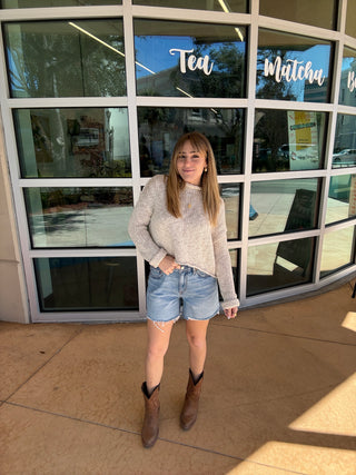 Person standing in front of a large window with reflections and store signs.