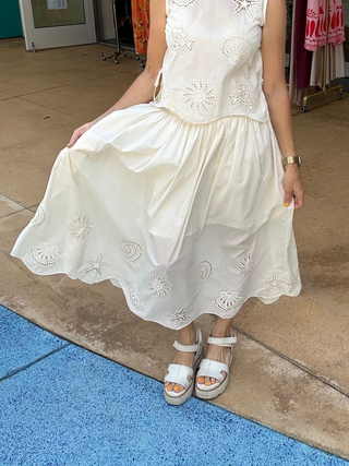 Woman wearing a cream skirt in front of a store entrance
