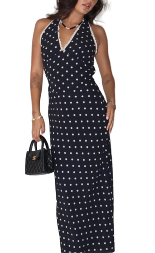 Woman wearing a black dress with white polka dots against a plain background