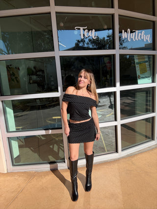 Person posing in front of a window with a store sign reflected Polka Dot Mini Skirt Black & White