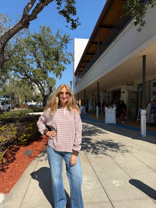 Woman standing on a sidewalk with a building and trees in the background