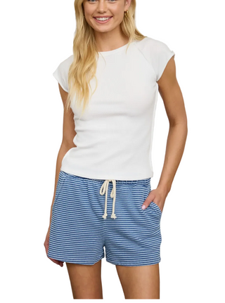 Woman wearing a white top and blue striped shorts in a laundry room.