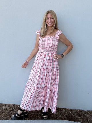 Woman wearing a red and white checkered dress against a light blue wall.