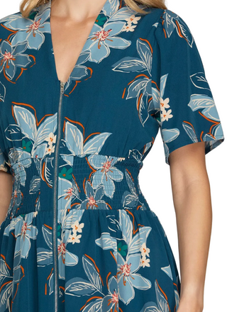 A close-up of a woman wearing a short-sleeve V-neck dress with a front zipper and a blue floral print with light blue, white, and orange accents.