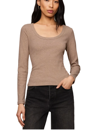 A woman modeling a fitted, long-sleeve scoop-neck knit top in a warm taupe-brown color, paired with black jeans, against a solid light beige studio background.