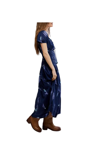 Woman wearing a blue floral dress with brown boots on a white background