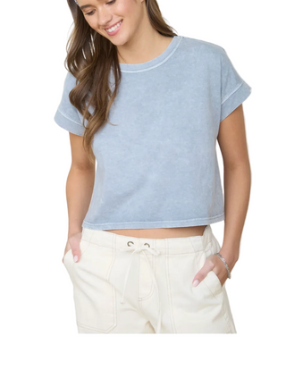 Woman wearing a light blue crop top and white pants in a casual setting.