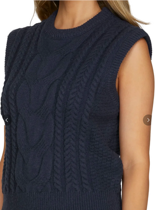 Navy blue knitted vest worn by a person on a plain background