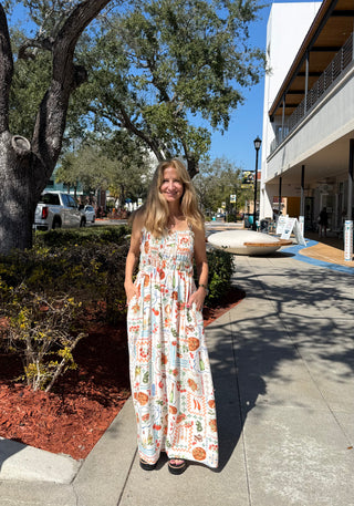 Woman in a patterned dress standing on a sidewalk with trees and buildings in the background