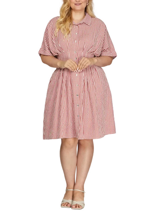A woman modeling a red and white gingham short-sleeve shirt dress with a tie waist, shown against a plain light gray studio background.