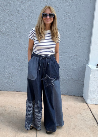 woman wearing patchwork denim drawstring pants standing against a blue background
