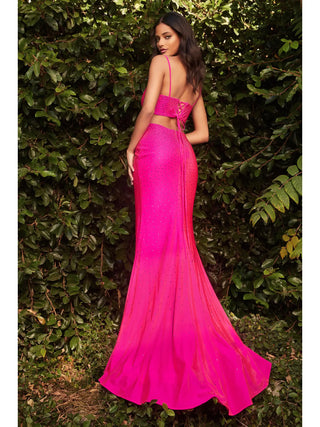 Woman wearing a bright pink evening gown against a green hedge.