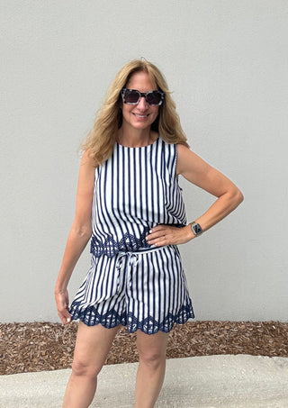 Woman wearing a blue and white striped dress with a belt against a plain background