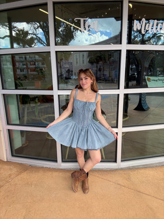 Woman in a blue dress posing in front of a glass window
