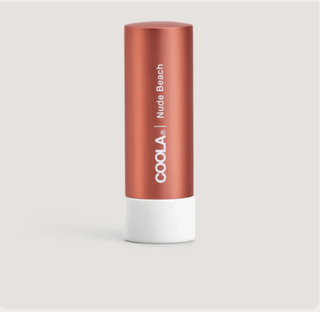 Coola lip balm with 'Nude Beach' and 'COOLA' branding on a light gray background